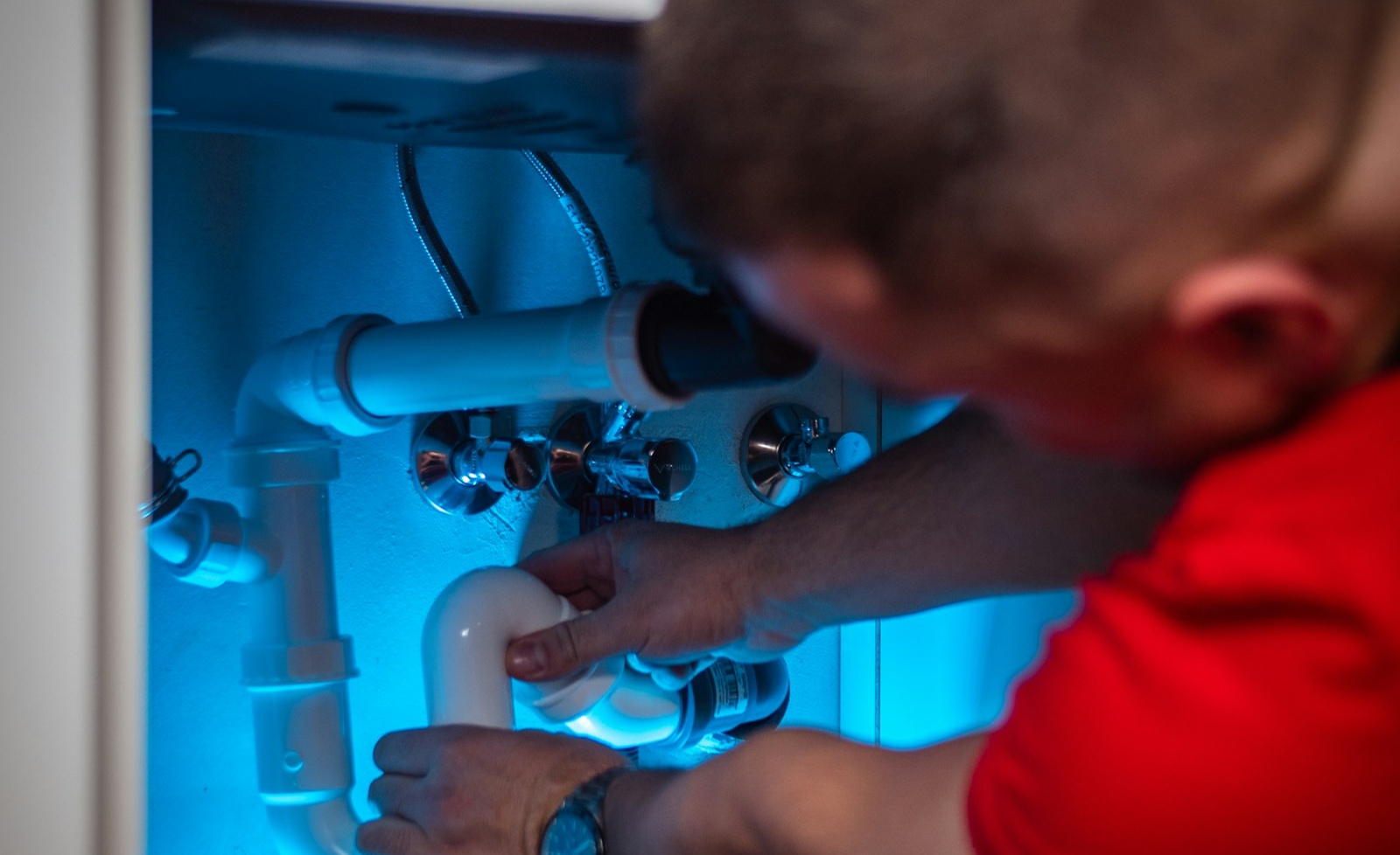 Plumber repairing pipework under a kitchen sink
